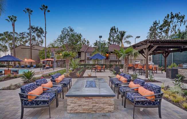 A patio with a fire pit surrounded by chairs and tables.