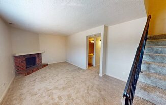 a living room with a staircase and a brick fireplace