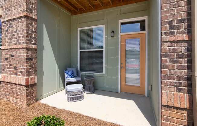 a porch with a chair and a stool in front of a door