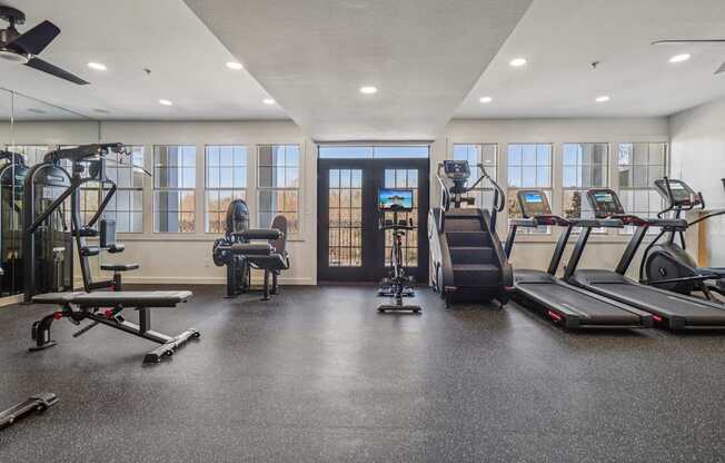 A spacious gym with a variety of equipment including treadmills, elliptical machines, and a bench press.