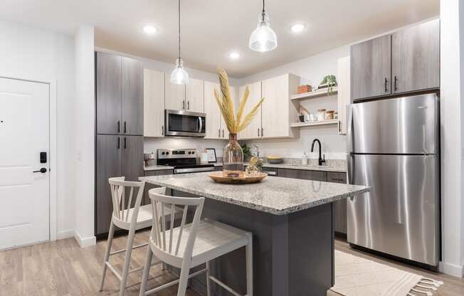 new apartment kitchen with stainless steel appliances, granite countertops, and pendant lights