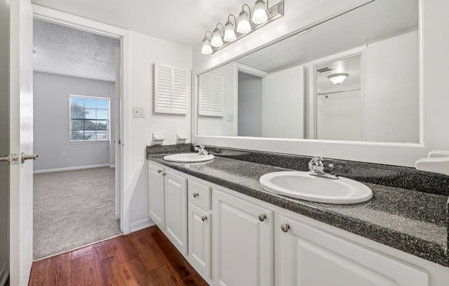 A bathroom with a sink, mirror, and wooden floors.