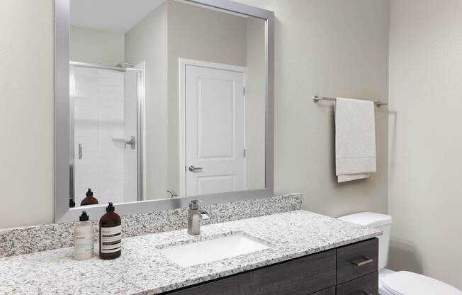 A bathroom with a white counter top and a toilet.