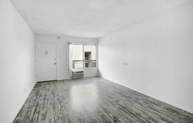 an empty living room with white walls and a window