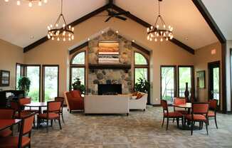 a large living room with a stone fireplace and tables and chairs