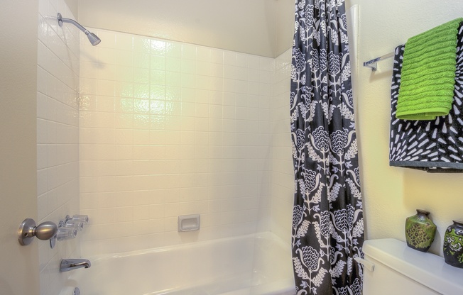 A bathroom with a shower curtain and a green towel.