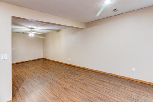 an empty living room with wood flooring and a ceiling fan