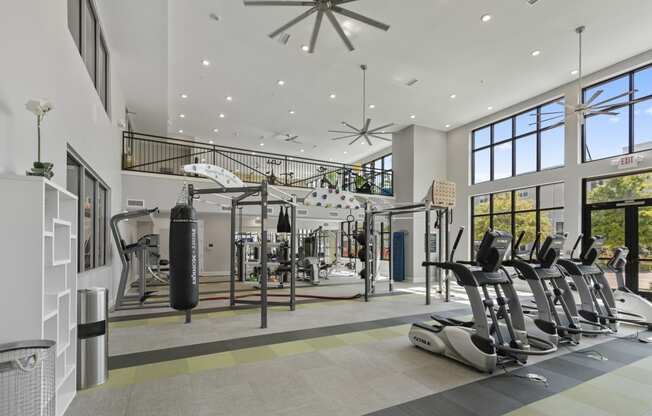 a gym with treadmills and weights in a building with large windows