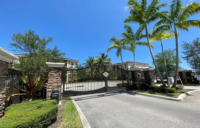A gated entrance to a residential area with a palm tree.