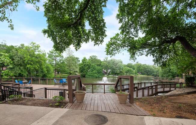 a deck overlooking a body of water with trees and a fountain