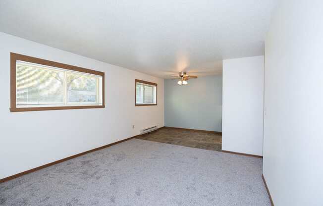 an empty living room with a ceiling fan and a window. Fargo, ND Pacific South Apartments