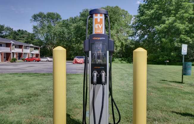 a gas pump sitting in the grass next to some yellow poles