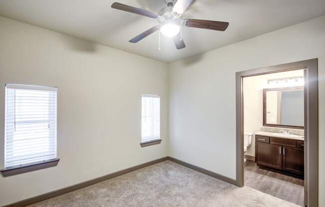 an empty bedroom with a ceiling fan and a mirror