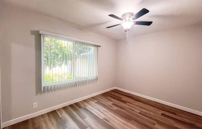 the spacious living room of a home with wood flooring and a ceiling fan