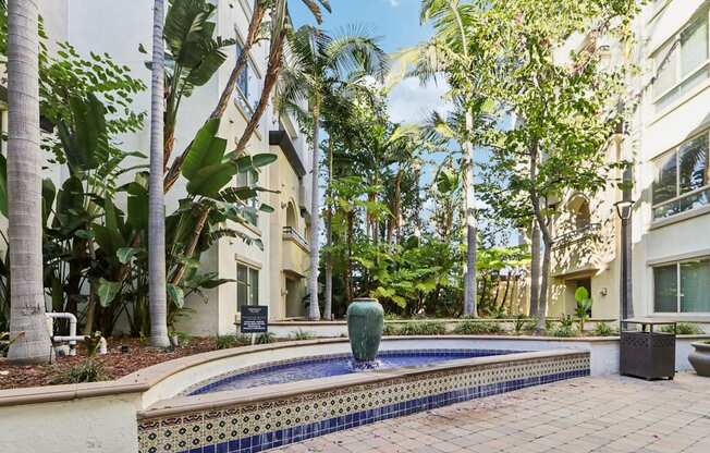 A pool surrounded by palm trees and a building in the background.