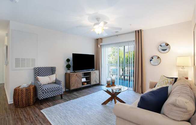 A living room with a chair, a sofa, a coffee table, and a television.