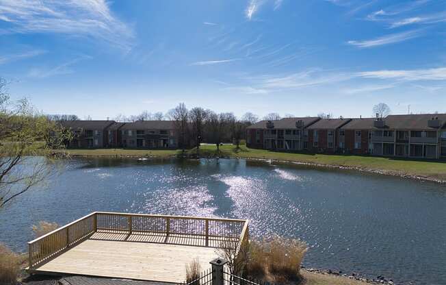 a large pond with a wooden dock in front of some apartments