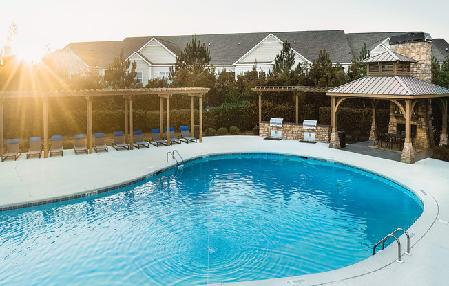 a swimming pool with chairs and a house in the background