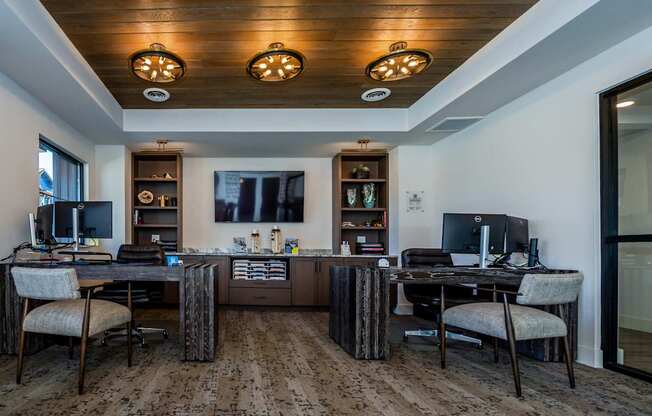 A room with two desks and chairs, one of which is a gaming chair.