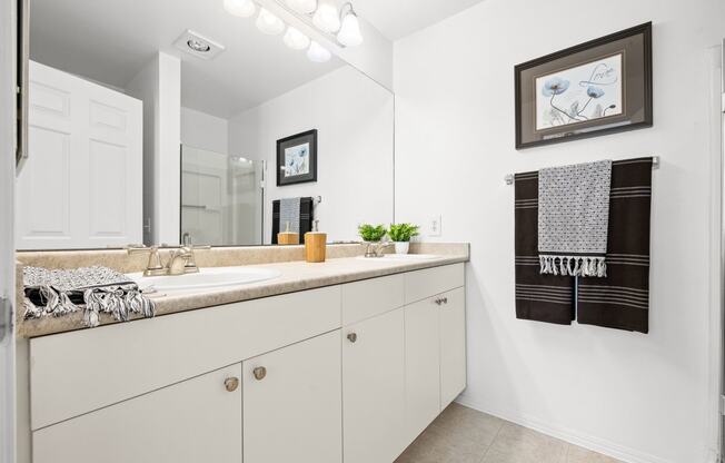 a bathroom with white cabinets and a large mirror