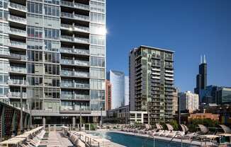an outdoor pool with lounge chairs next to a tall building in the chicago skyline