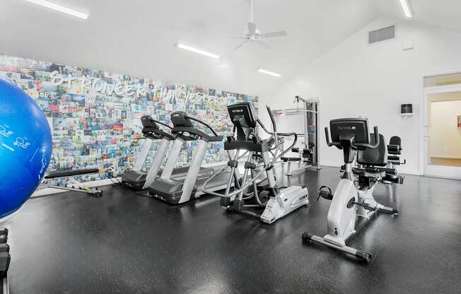 A gym with a wall covered in graffiti and exercise equipment.