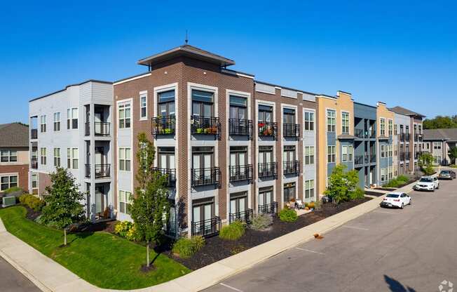 A row of modern apartment buildings with cars parked in front.