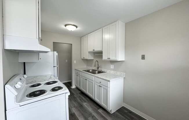 an empty kitchen with white appliances and white cabinets