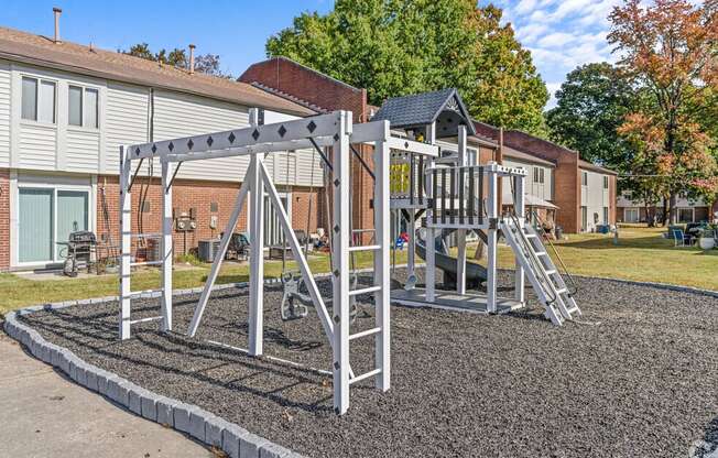 a playground with a swing set in front of a house