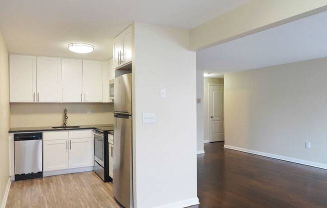 an empty kitchen with white cabinets and a stainless steel refrigerator at The Packard, West Hartford