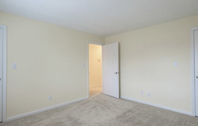 A room with two doors and carpeted floor.