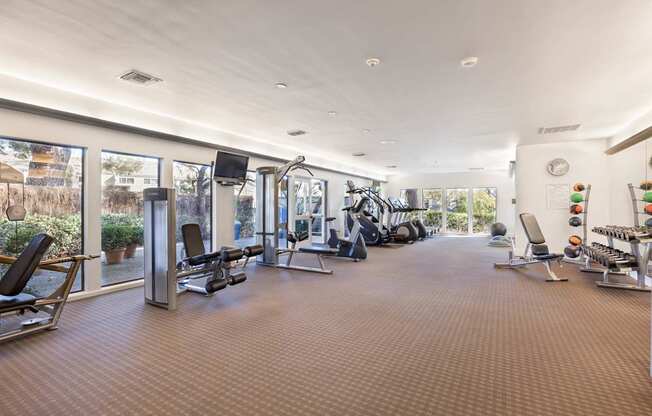 A spacious gym with a variety of equipment and a large mirror on the wall.
