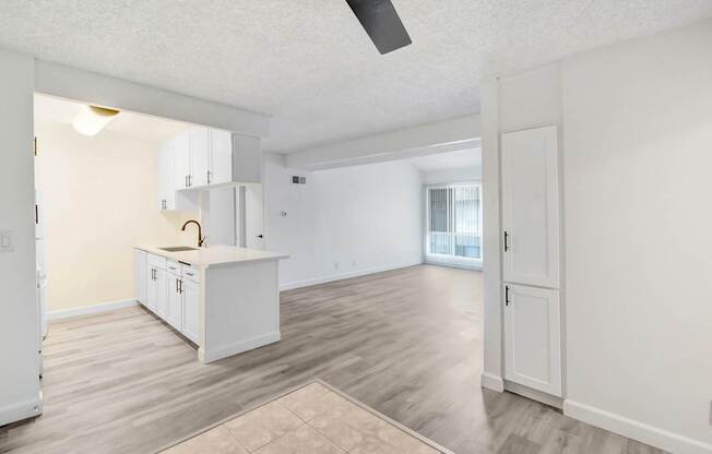 A kitchen with white cabinets and a ceiling fan.