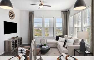 A living room with a large couch, a television, and a ceiling fan.