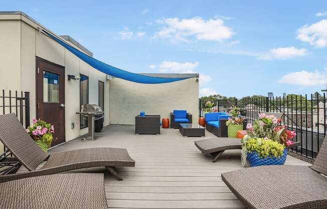 a rooftop deck with chairs and a grill and a blue roof