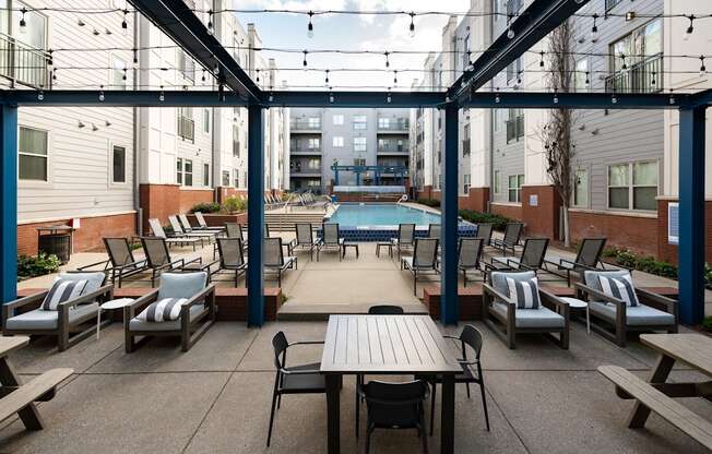 a patio with tables and chairs and a pool in the middle of an apartment building