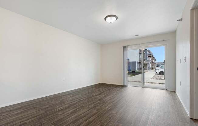 A room with a wooden floor and a sliding glass door leading to a balcony.