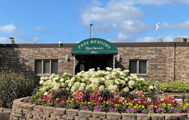 a flower bed in front of a brick building with a green awning