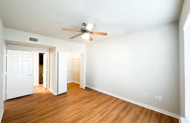 an empty living room with a ceiling fan and wood floors