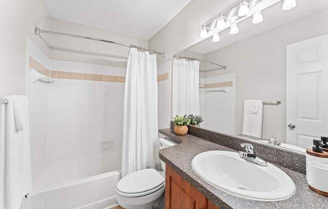 A white bathroom with a toilet, sink, and shower.