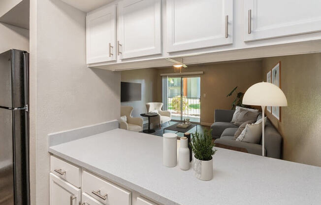 Model Kitchen with White Cabinets and Living Room View at Indigo Park Apartments in Albuquerque, NM.
