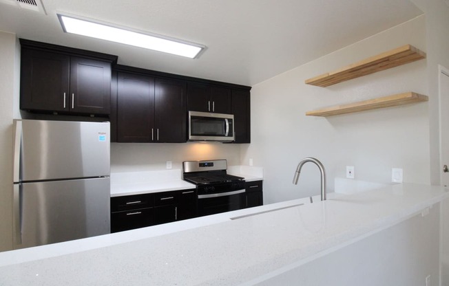 a apartment kitchen with upgraded black cabinets and a white counter top