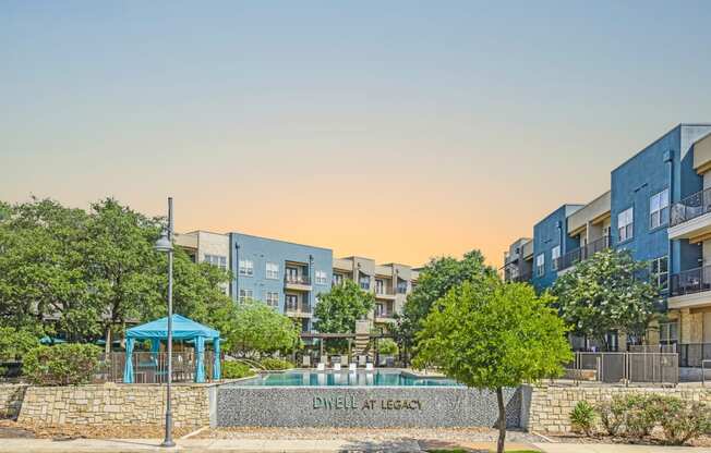 an apartment building with a pool and trees in front of it