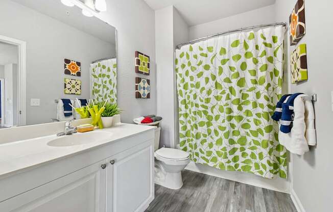 A bathroom with a white sink, toilet, and a green shower curtain.