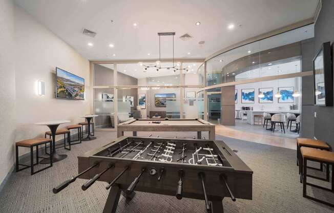 A room with a foosball table in the center and a bar area to the left at Harbor Pointe Apartments, Bayonne 07002