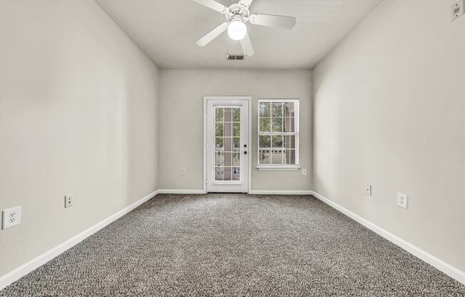 an empty living room with a ceiling fan and a window