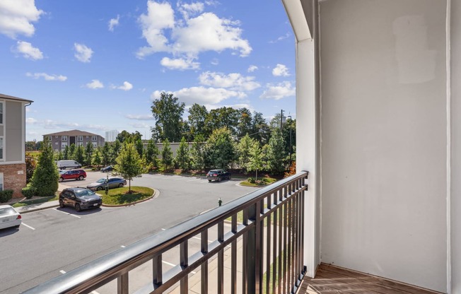 a balcony with a view of a parking lot and trees