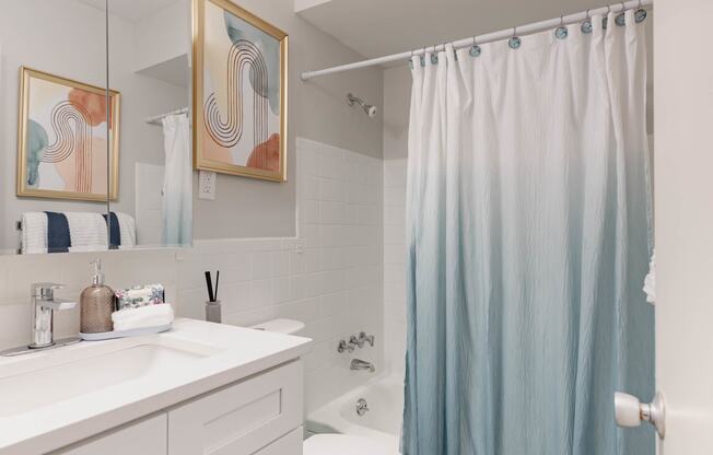 a white bathroom with a blue shower curtain and a toilet