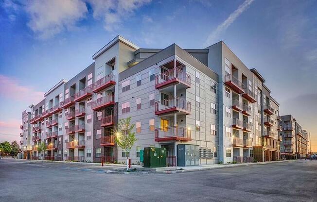 A modern apartment building with balconies and a parking lot in front.