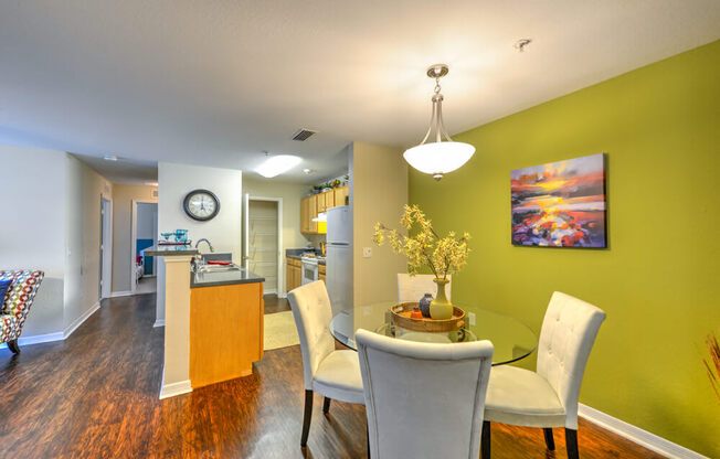 A dining room with a table set for two and a painting on the wall.